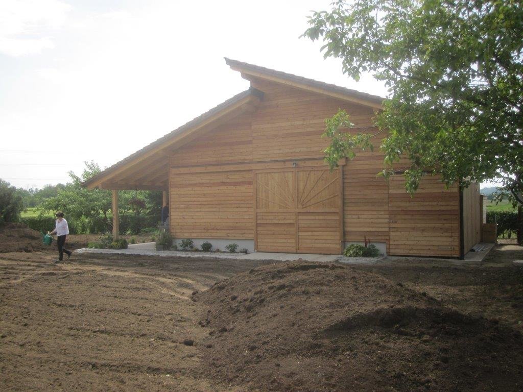 Großes, ausladendes Gartenhaus vor frisch angelegter Rasenfläche